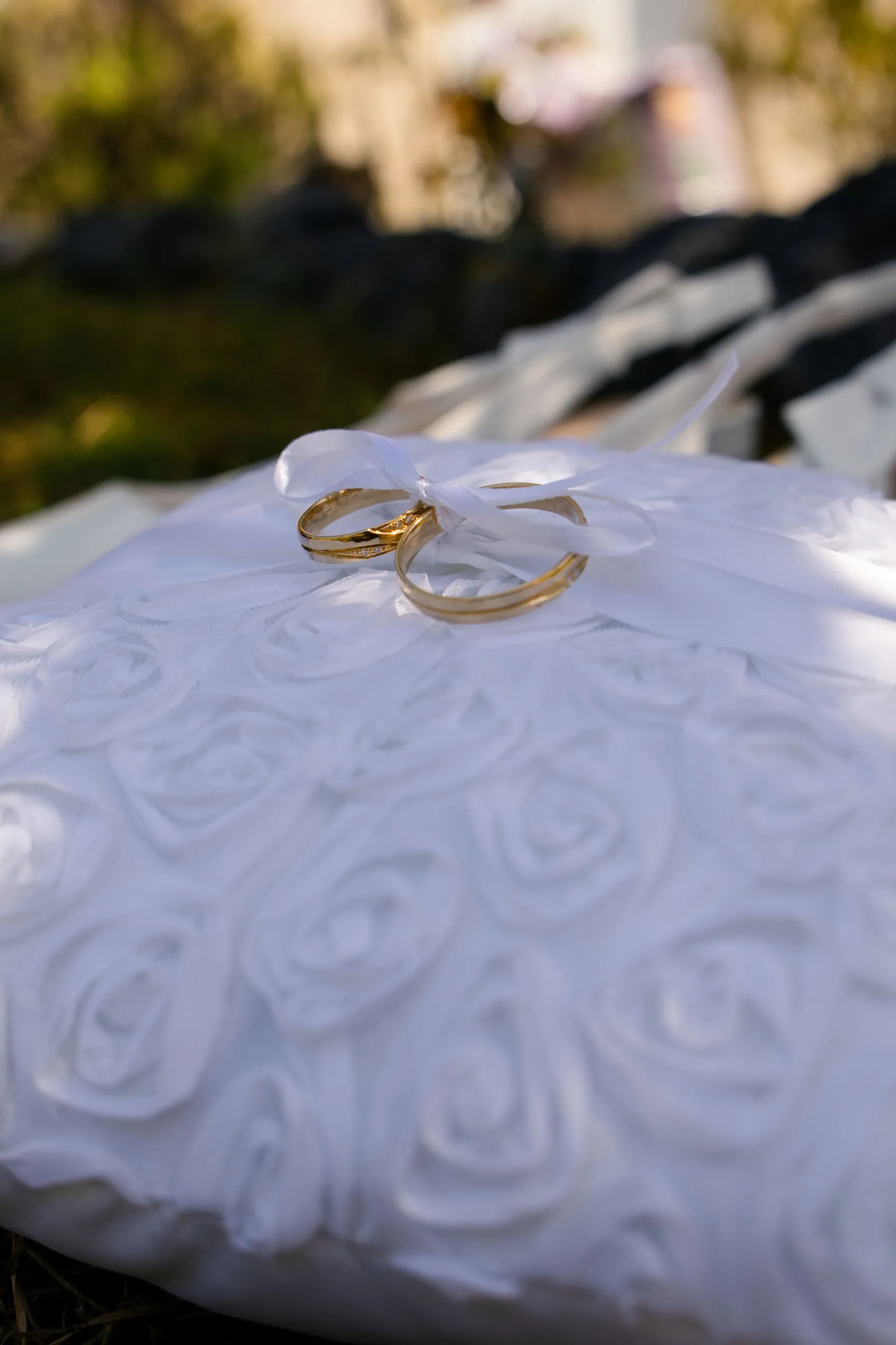 Alliances dorées posées sur un coussin de satin blanc, détail de mariage - Cindy Poulet photographe