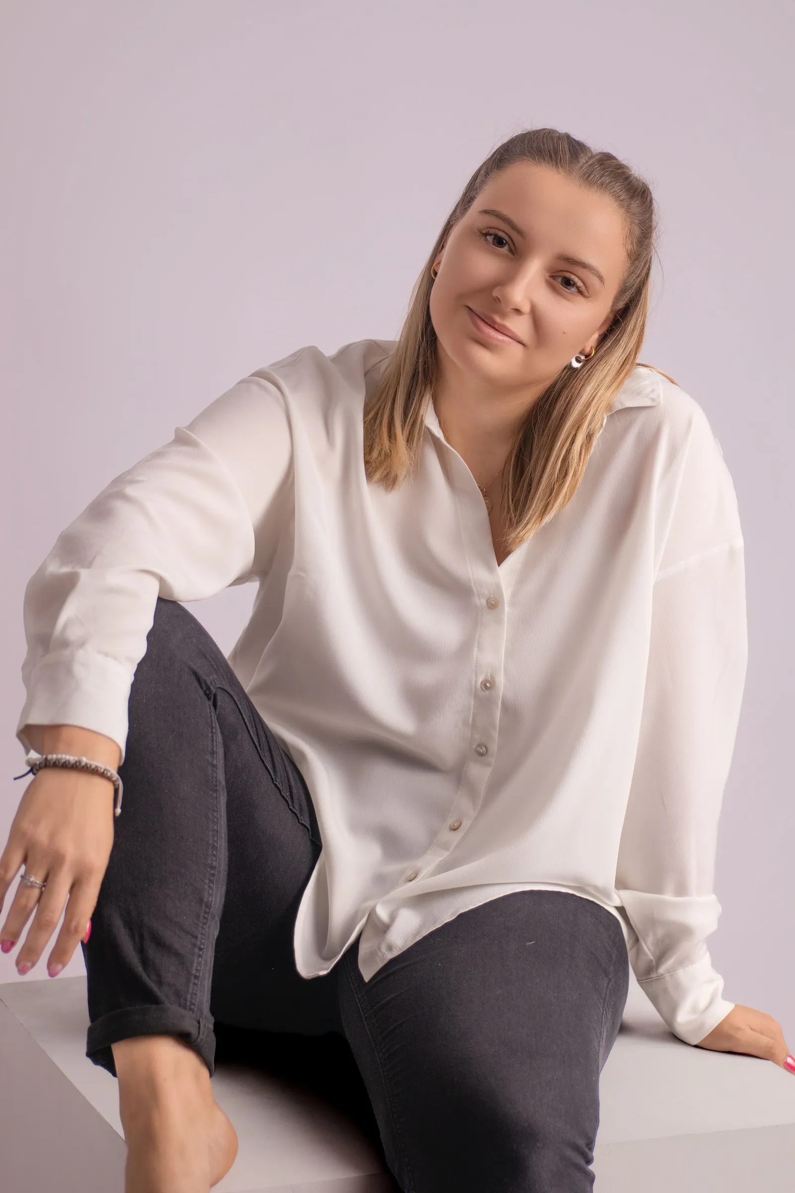 Portrait de studio d'une femme souriante en chemise blanche, par Cindy Poulet Photographe à Septvaux.