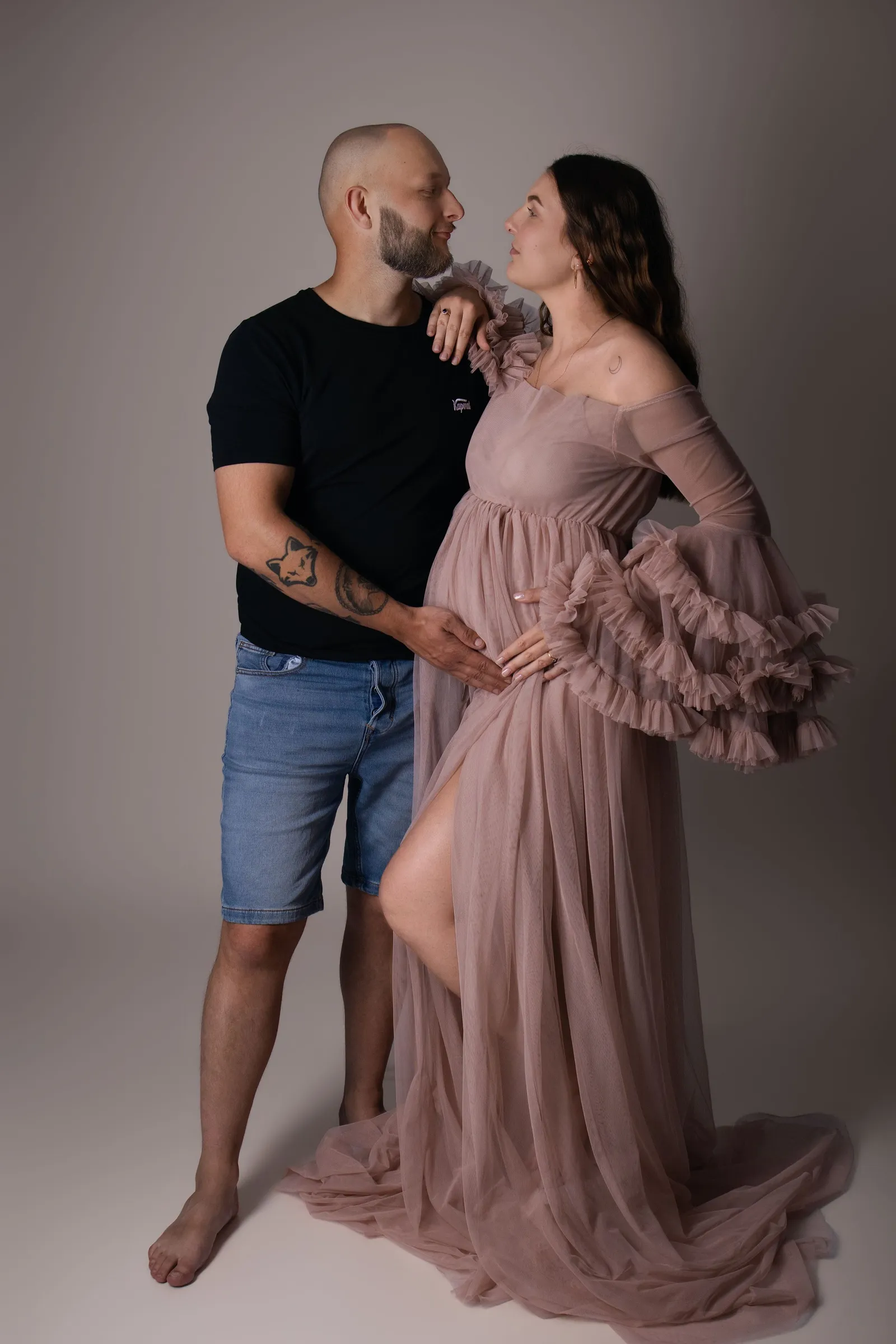 Couple attendant un bébé avec la femme en robe rose drapée, portrait maternité studio - Cindy Poulet photographe