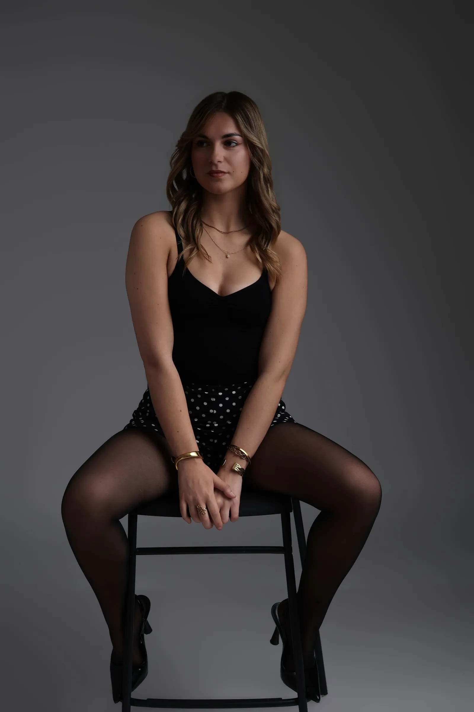 Femme en tenue noire assise sur un cube blanc, portrait studio - Cindy Poulet photographe