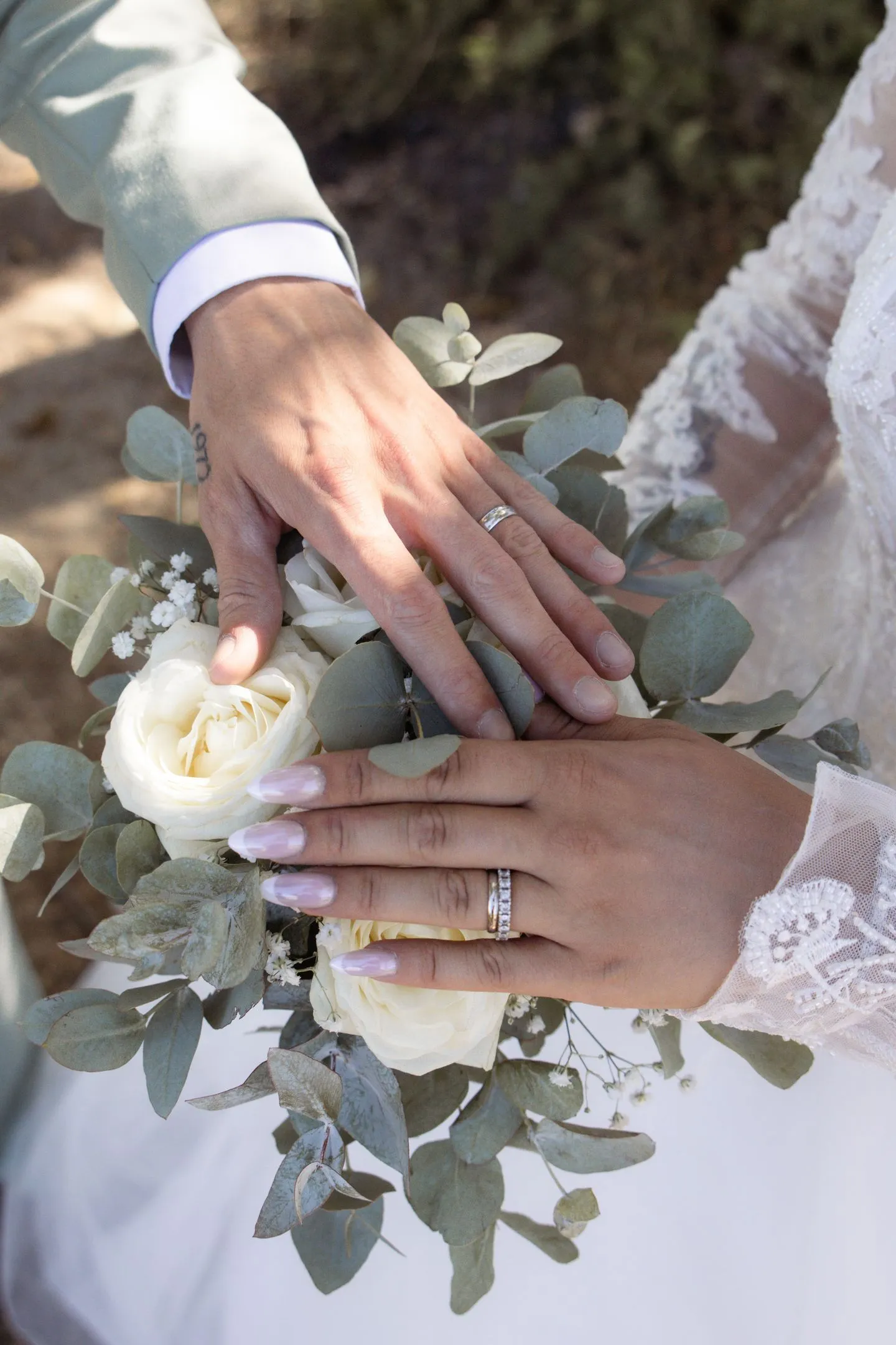 Mains des mariés posées sur le bouquet, alliances et roses blanches - Cindy Poulet photographe