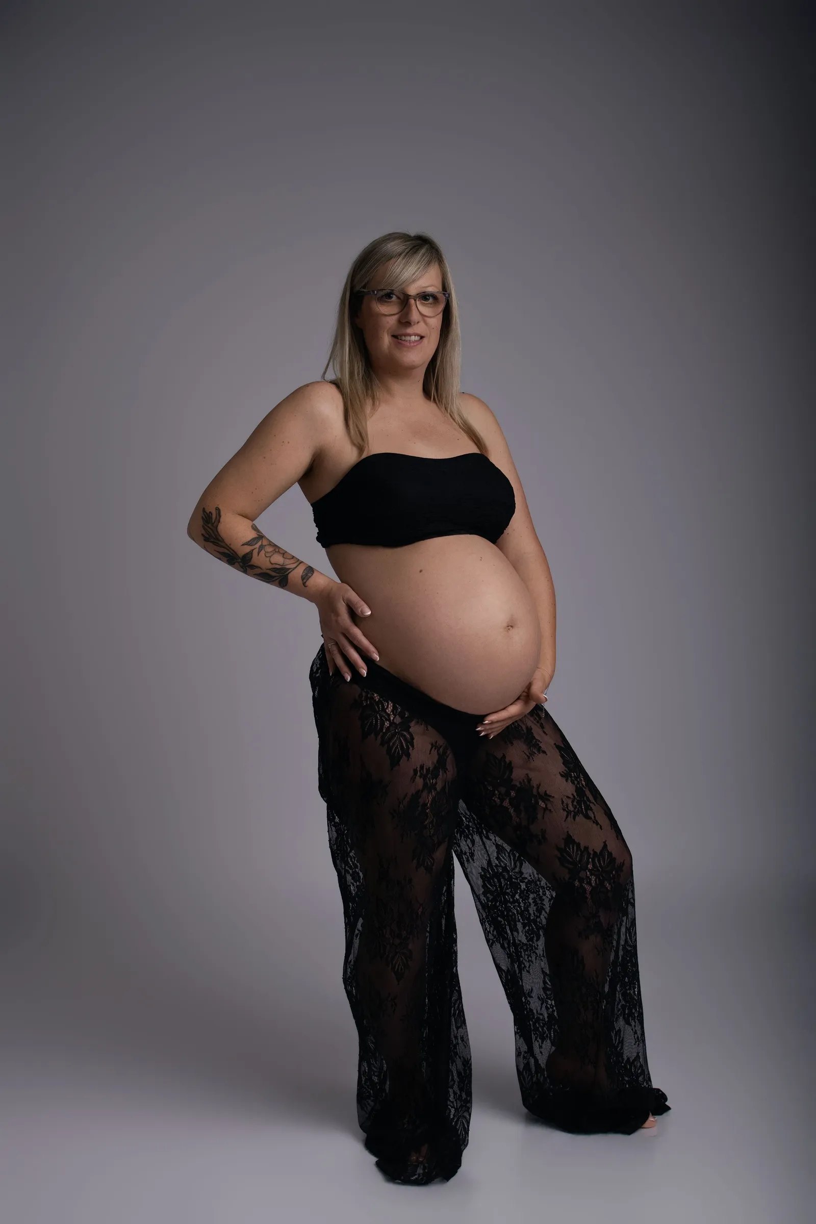 Femme enceinte en pantalon noir posant en studio, portrait maternité - Cindy Poulet photographe