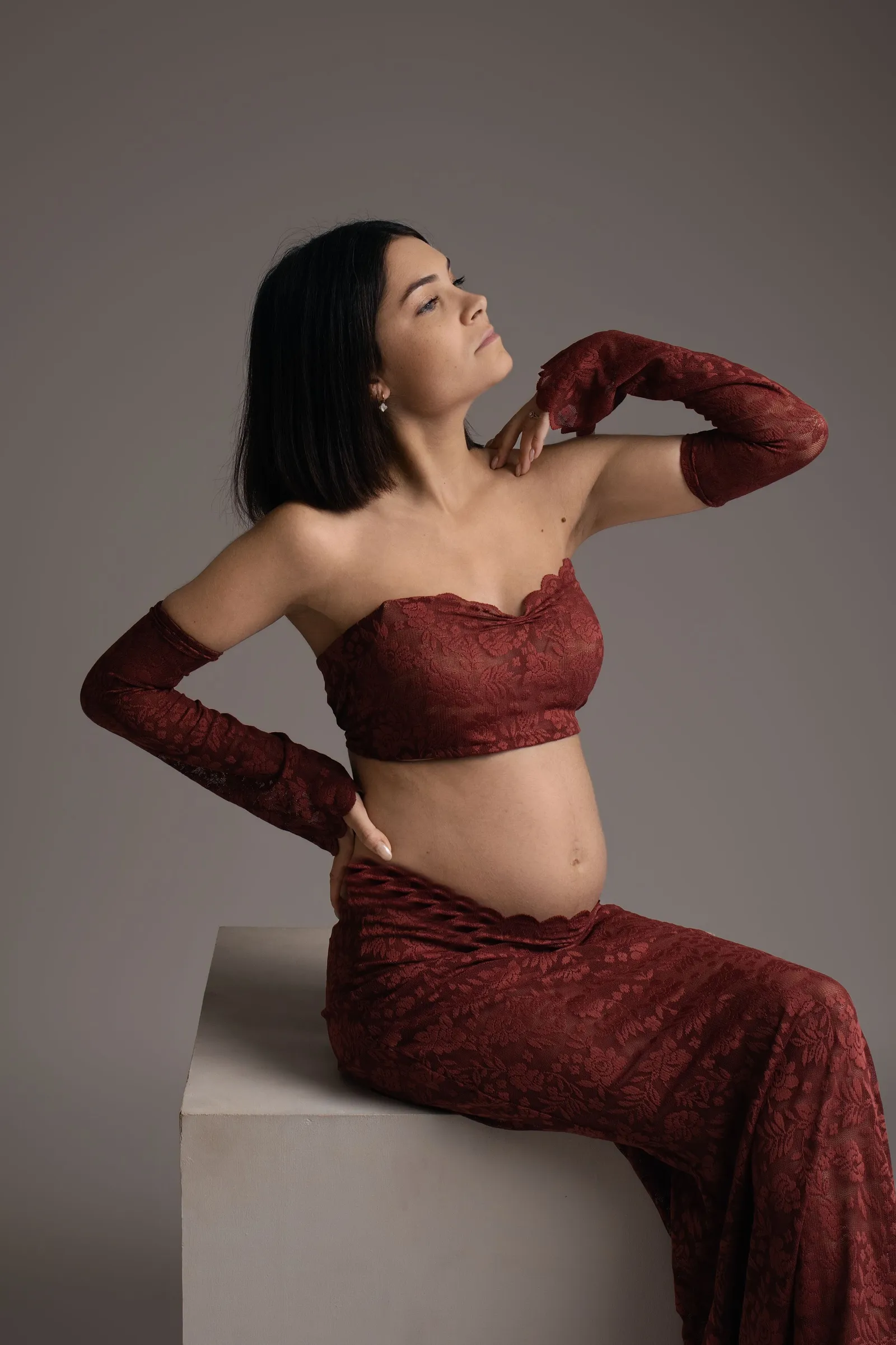 Femme enceinte en rouge assise, séance photo maternité en studio - Cindy Poulet photographe