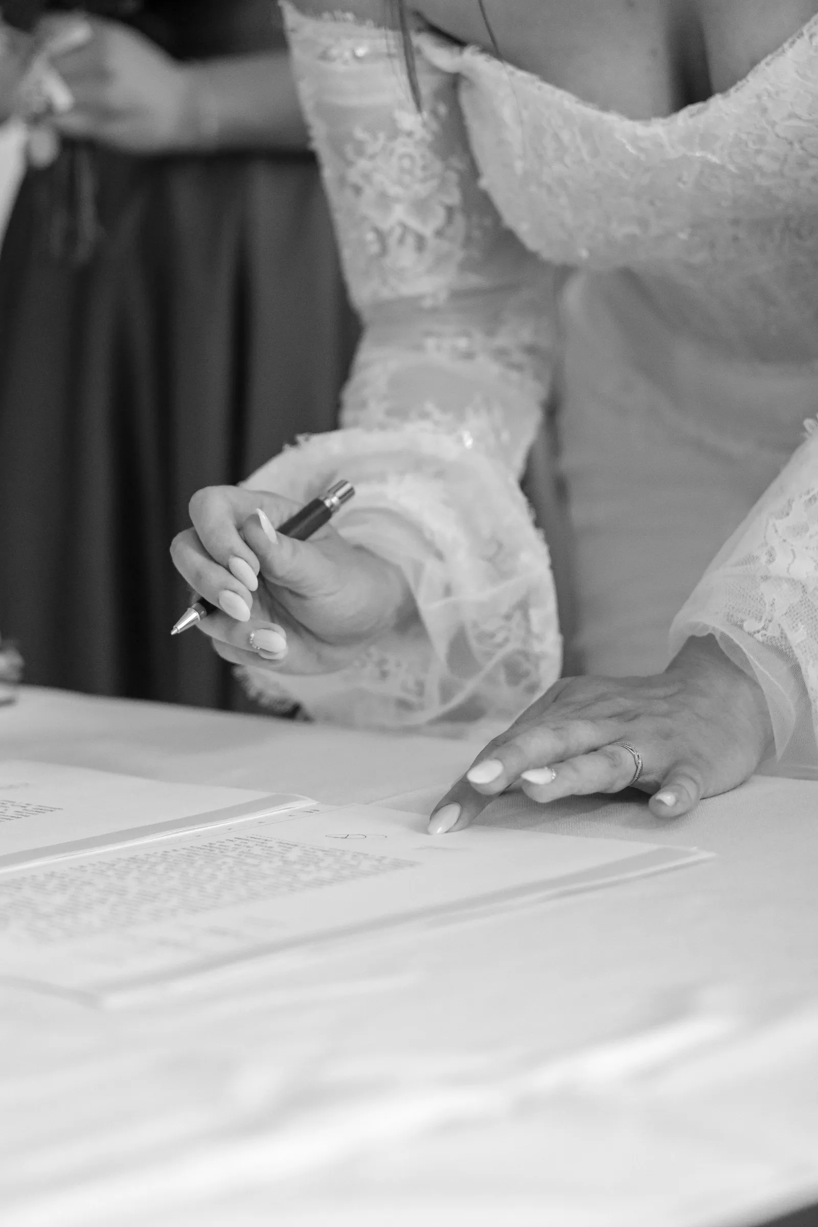 Mains de la mariée signant les registres de mariage, gros plan en noir et blanc - Cindy Poulet photographe