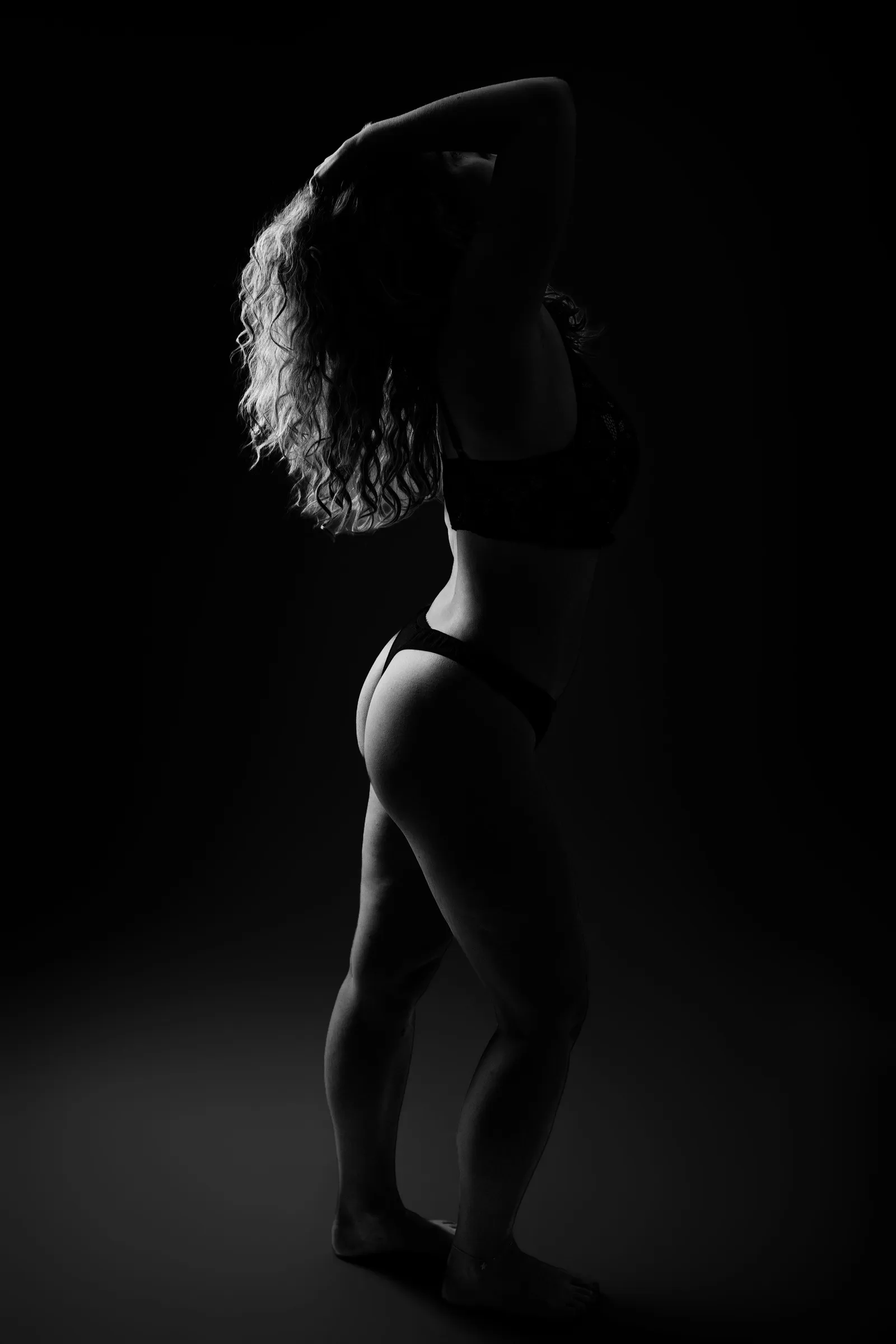 Femme de profil en lingerie noire, mains dans les cheveux, portrait boudoir en noir et blanc - Cindy Poulet photographe