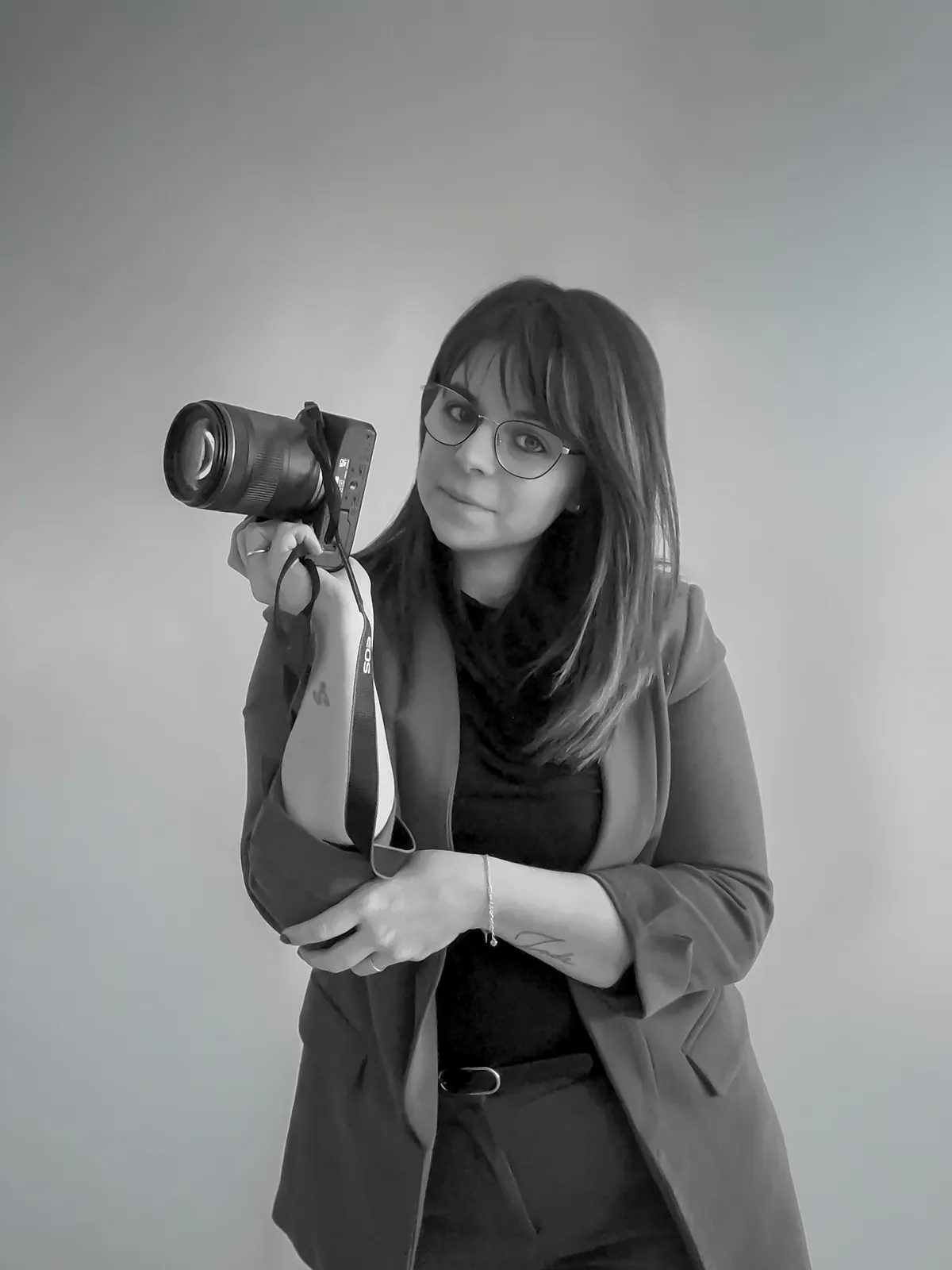 Portrait en noir et blanc de Cindy Poulet, photographe à Septvaux, son appareil photo à la main.