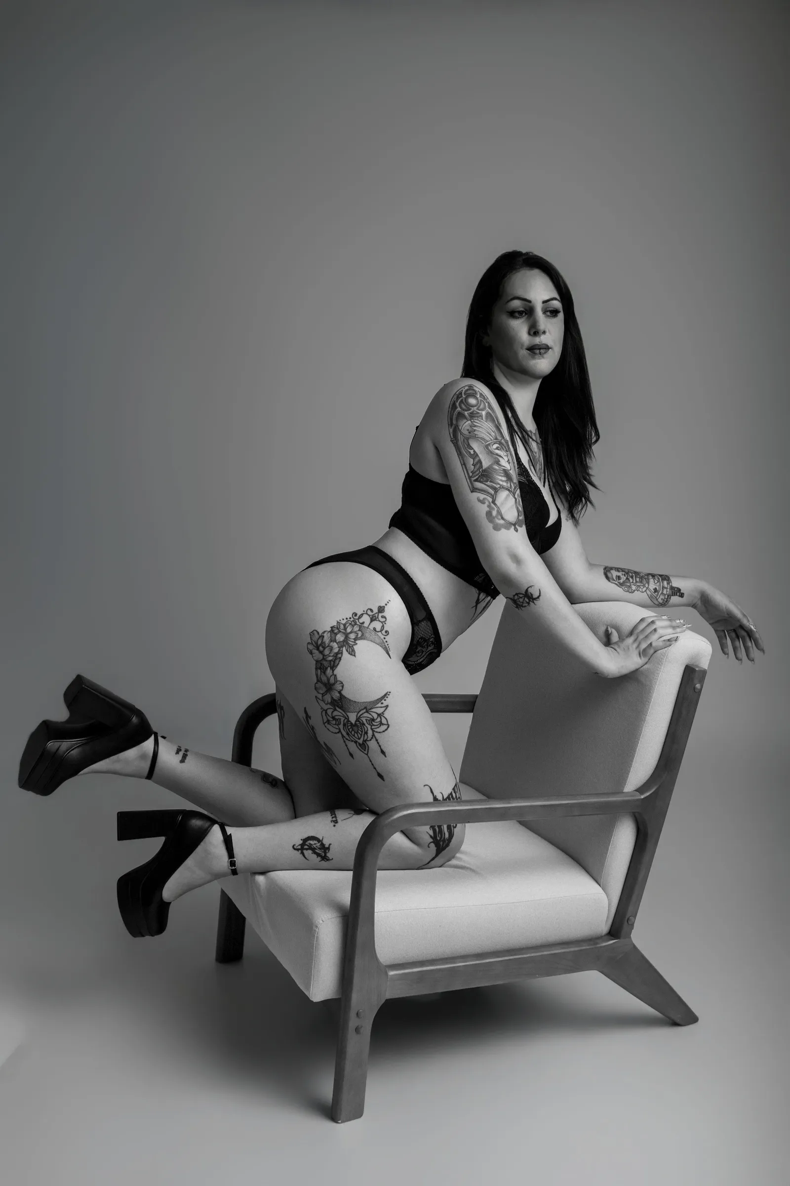 Femme tatouée posant à genoux sur une chaise en noir et blanc - Cindy Poulet photographe