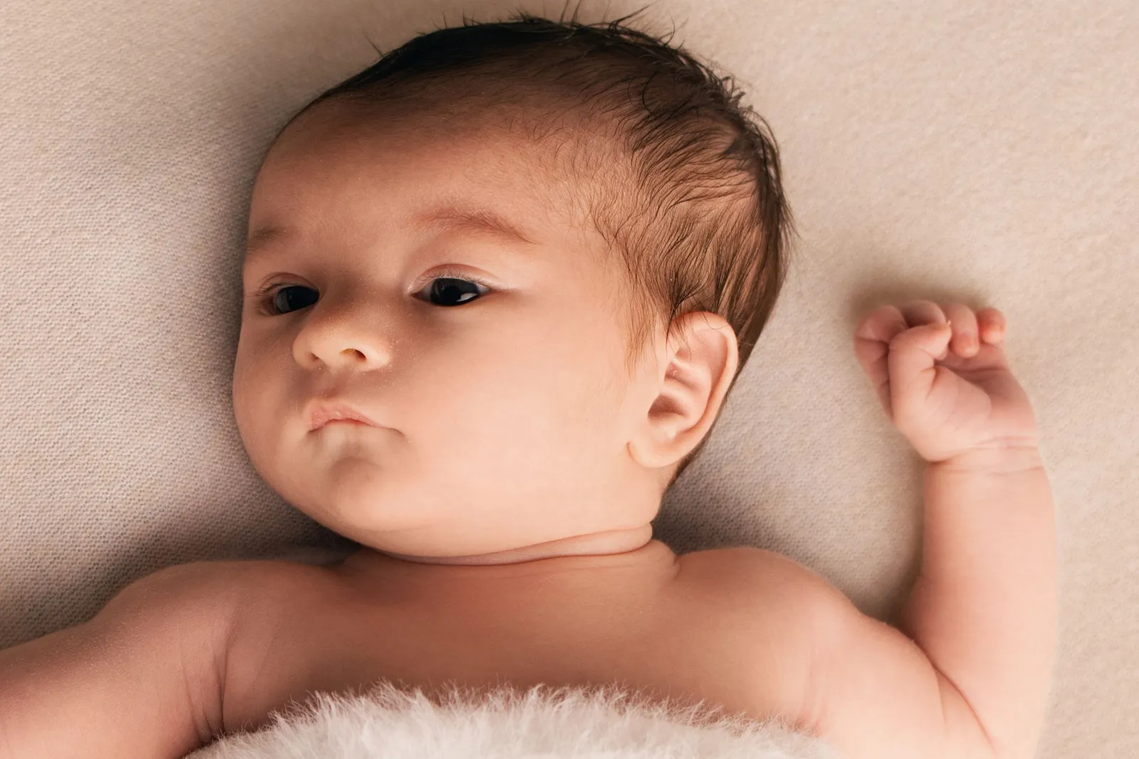 Photographie de nouveau-né par Cindy Poulet Photographe : portrait d'un bébé éveillé aux tons chauds et naturels lors d'une séance photo naissance