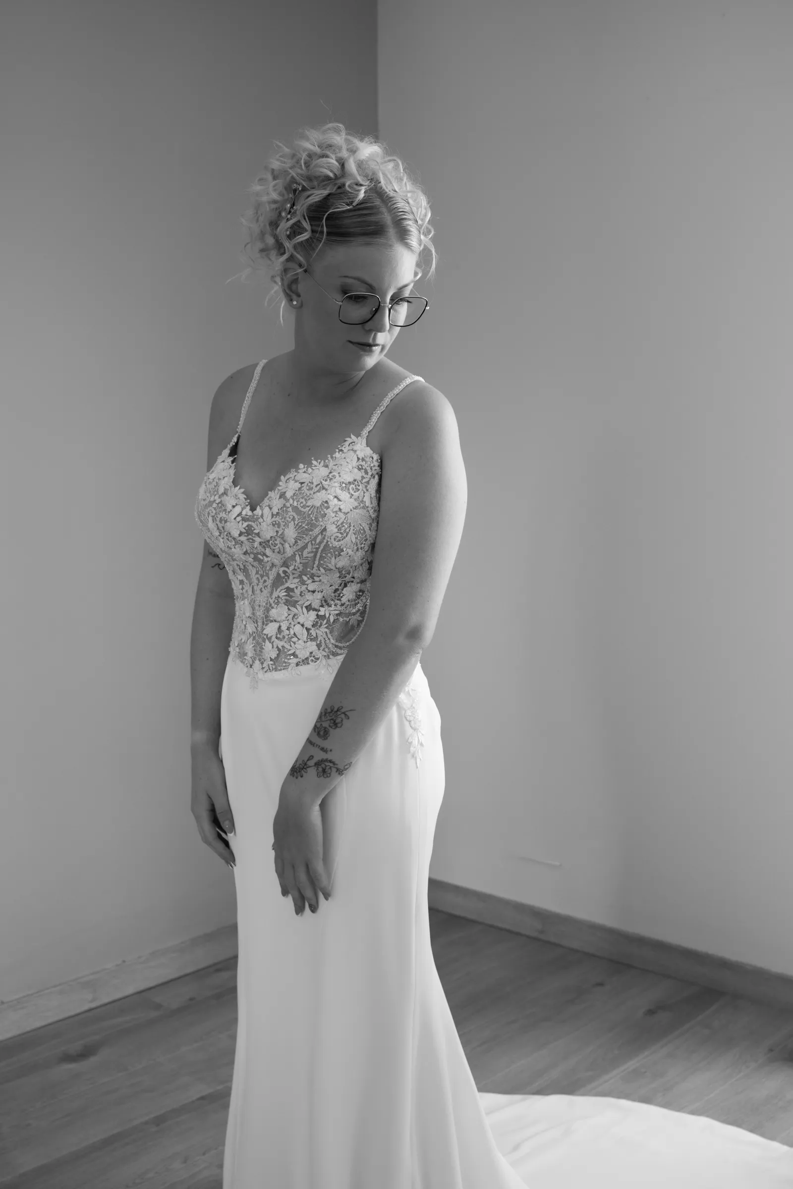 Mariée en robe à bustier de dentelle, regard baissé, préparatifs de mariage en noir et blanc - Cindy Poulet photographe