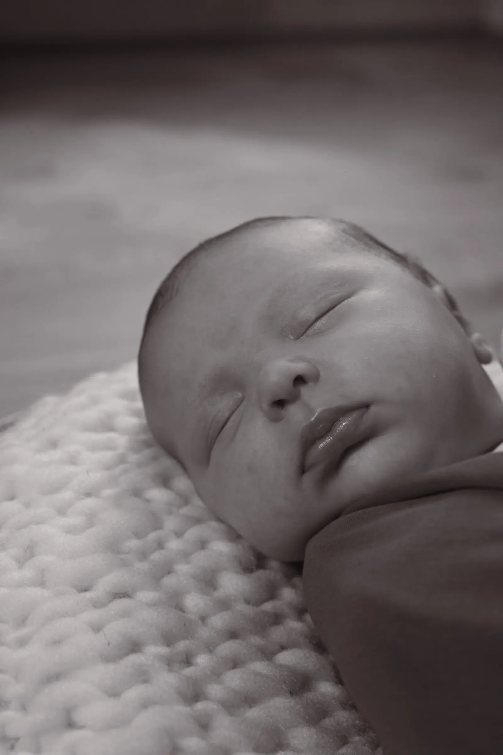 Portrait en noir et blanc d'un nouveau-né endormi sur une couverture douce, séance naissance - Cindy Poulet photographe