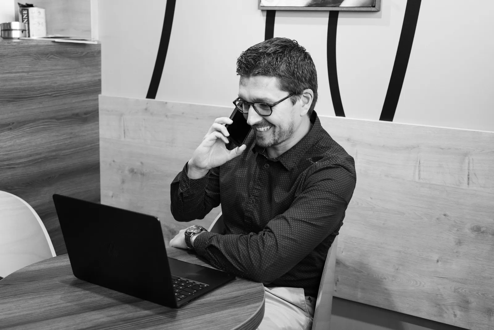 Portrait professionnel lifestyle par Cindy Poulet Photographe : homme souriant au téléphone devant son ordinateur portable dans son bureau.
