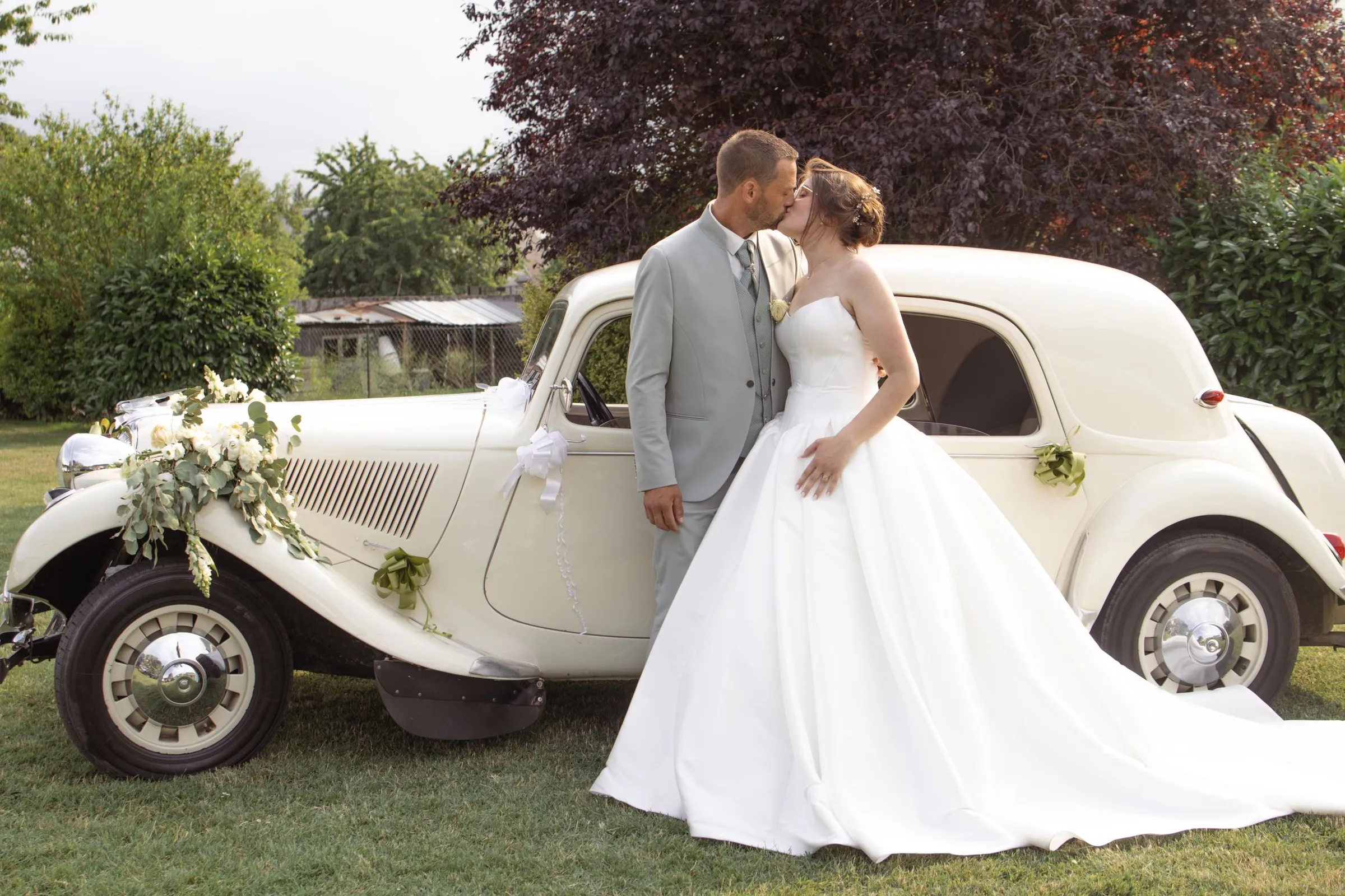 Mariés s'embrassant devant une voiture ancienne fleurie, mariage dans l'Aisne - Cindy Poulet photographe