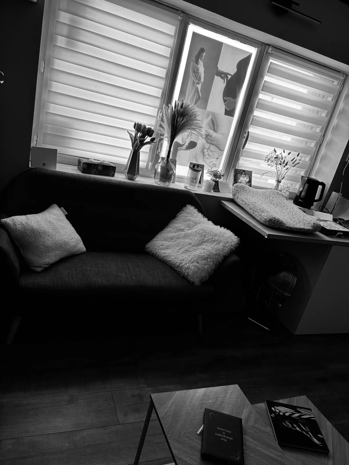 Studio Cindy Poulet Photographe : coin accueil chaleureux avec canapé gris, coussins moelleux et table à langer pour vos shootings nouveau-né et famille.