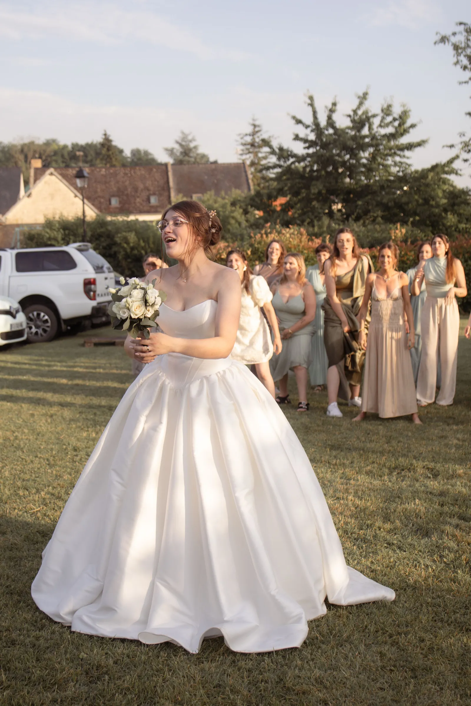 Mariée riant au moment du lancer de bouquet, demoiselles d'honneur derrière elle - Cindy Poulet photographe