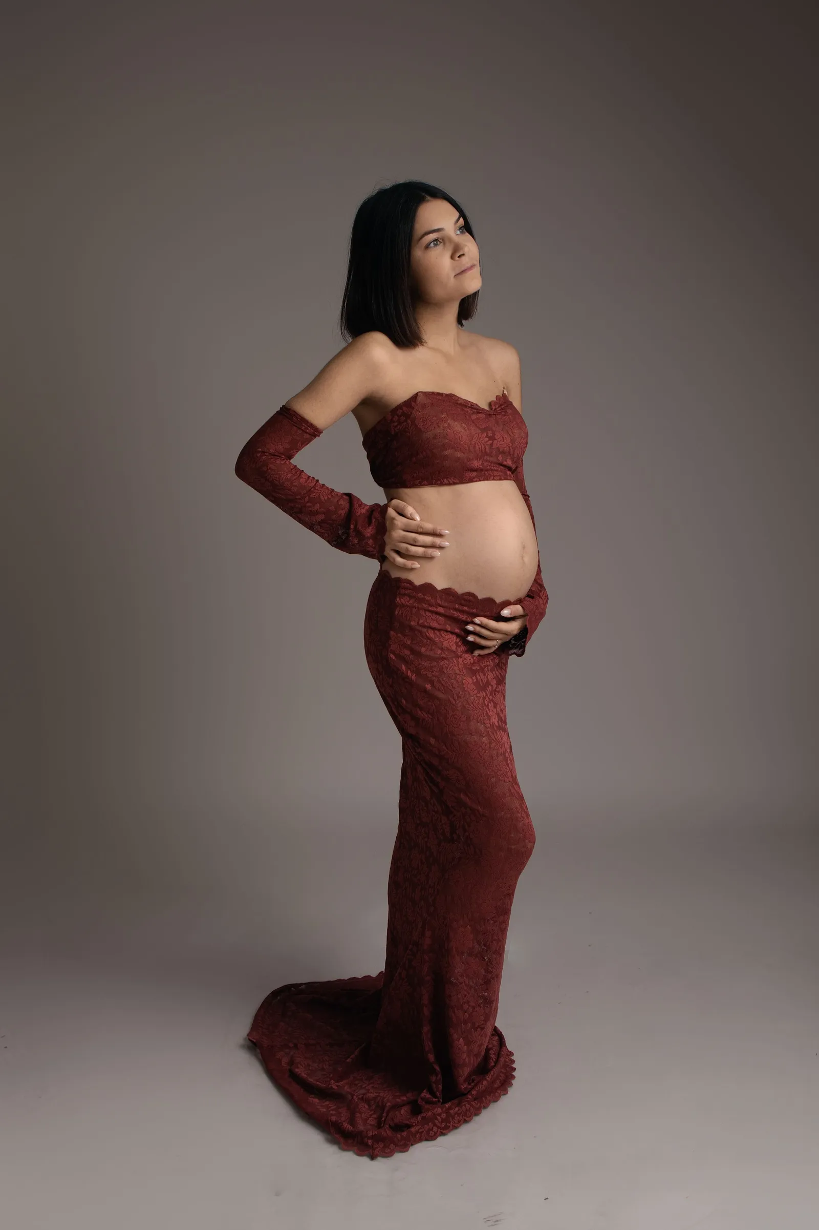 Femme enceinte en dentelle bordeaux, mains sur son ventre rond, portrait maternité en studio - Cindy Poulet photographe